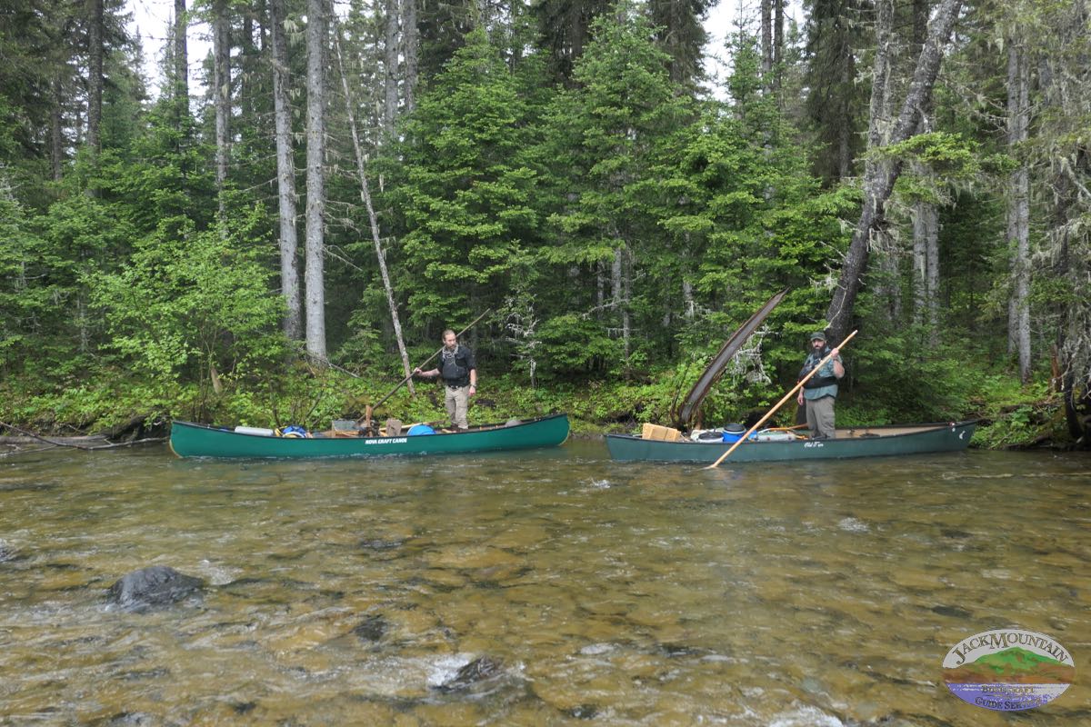 two people taking a break from poling canoes on a remote river